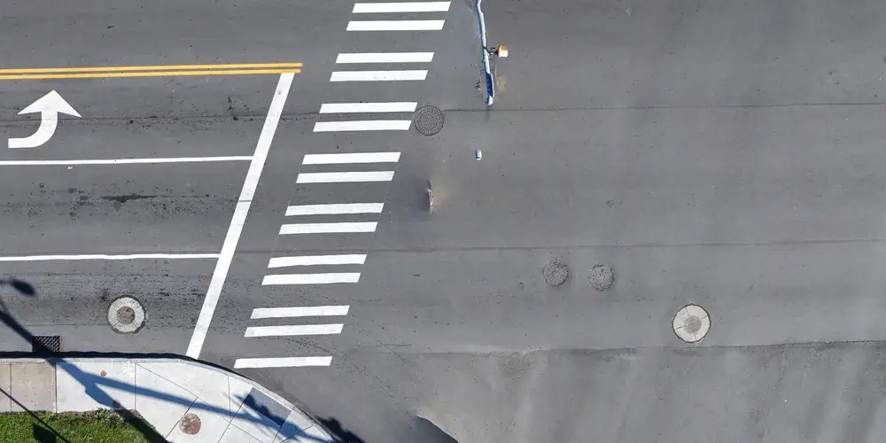 Detail from a drone orthomosaic of a paved corridor showing lane lines and an intersection