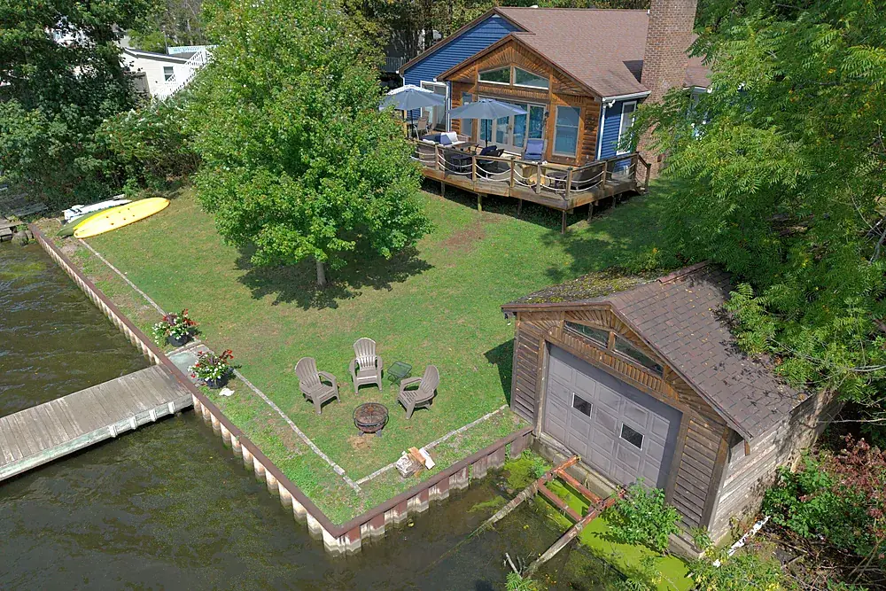 Aerial view of a lakefront back yard, fire pit and private dock in Monroe County, New York