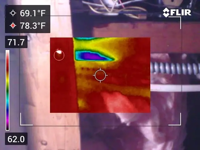 Thermal image overlaid on a normal photo showing a cold spot on a wall panel beside an exhaust duct