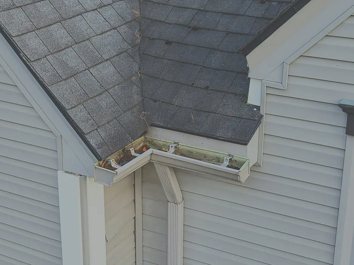 Aerial close-up of a gutter and fascia corner with accumulated debris